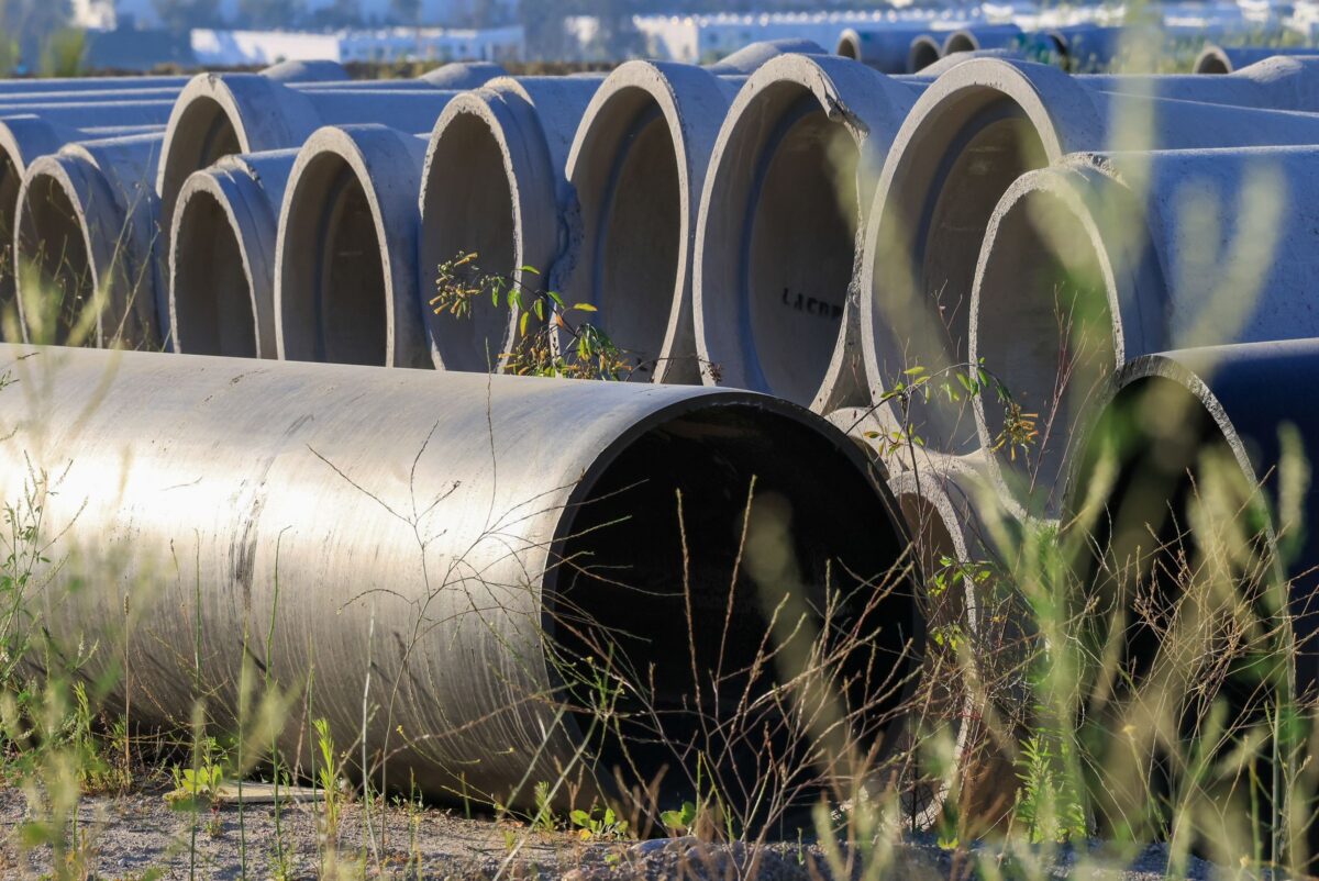 Tuyau PVC noir de cure posé sur une dalle de béton frais pour la maintenir humide