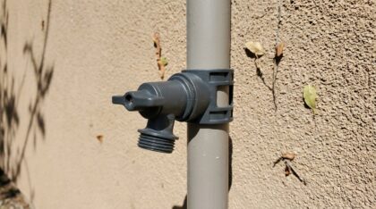 Robinet extérieur en laiton fixé sur une façade, avec tuyau d'arrosage raccordé